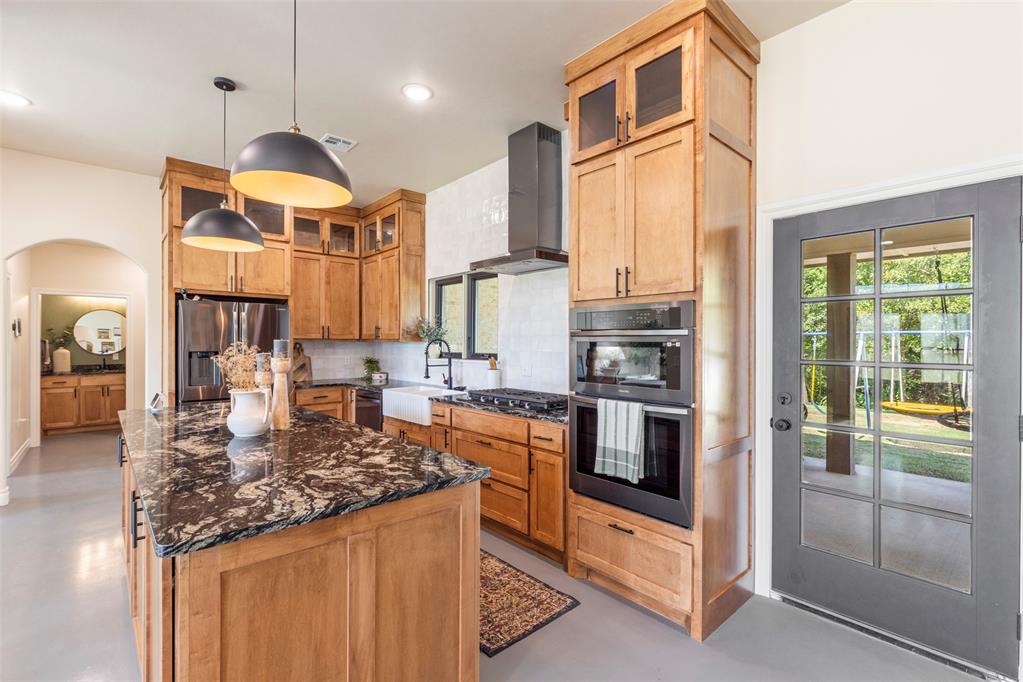 Tessa Hood Realtor – Kitchen with granite island, wood cabinetry, range hood, and stainless appliances at 1074 Fawn Meadow Dr, Blanchard Oklahoma