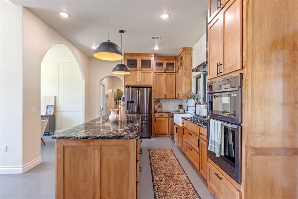 Tessa Hood Realtor – Kitchen showing granite island, abundant cabinetry, stainless refrigerator, and double oven at 1074 Fawn Meadow Dr, Blanchard Oklahoma