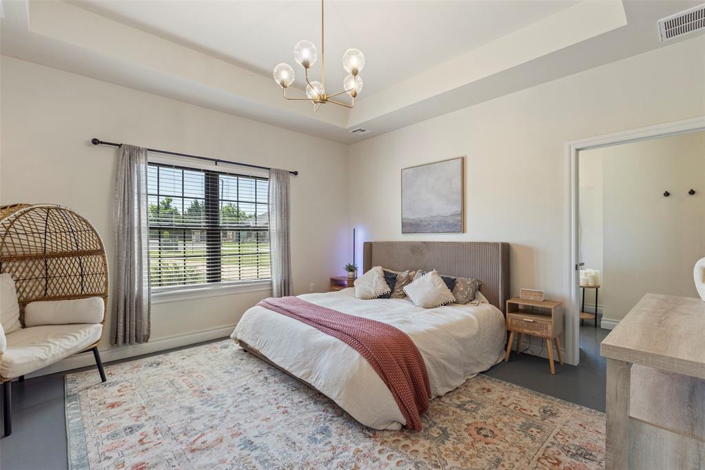 Tessa Hood Realtor – Primary bedroom with tray ceiling, gold chandelier, and walk-in closet entry at 1074 Fawn Meadow Dr, Blanchard Oklahoma