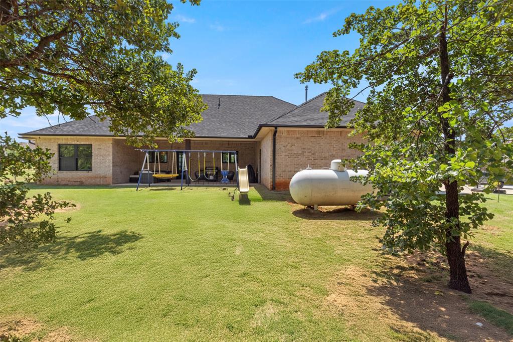 Tessa Hood Realtor – Backyard with play set and wooded tree line at 1074 Fawn Meadow Dr, Blanchard Oklahoma