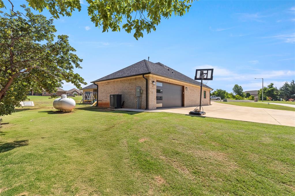 Tessa Hood Realtor – Garage side view with basketball hoop and extended driveway at 1074 Fawn Meadow Dr, Blanchard Oklahoma