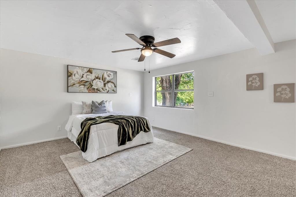 Tessa Hood Realtor – Primary bedroom with new carpet, ceiling fan, and mature tree window view at 7400 Lakewood Dr, Mustang Oklahoma