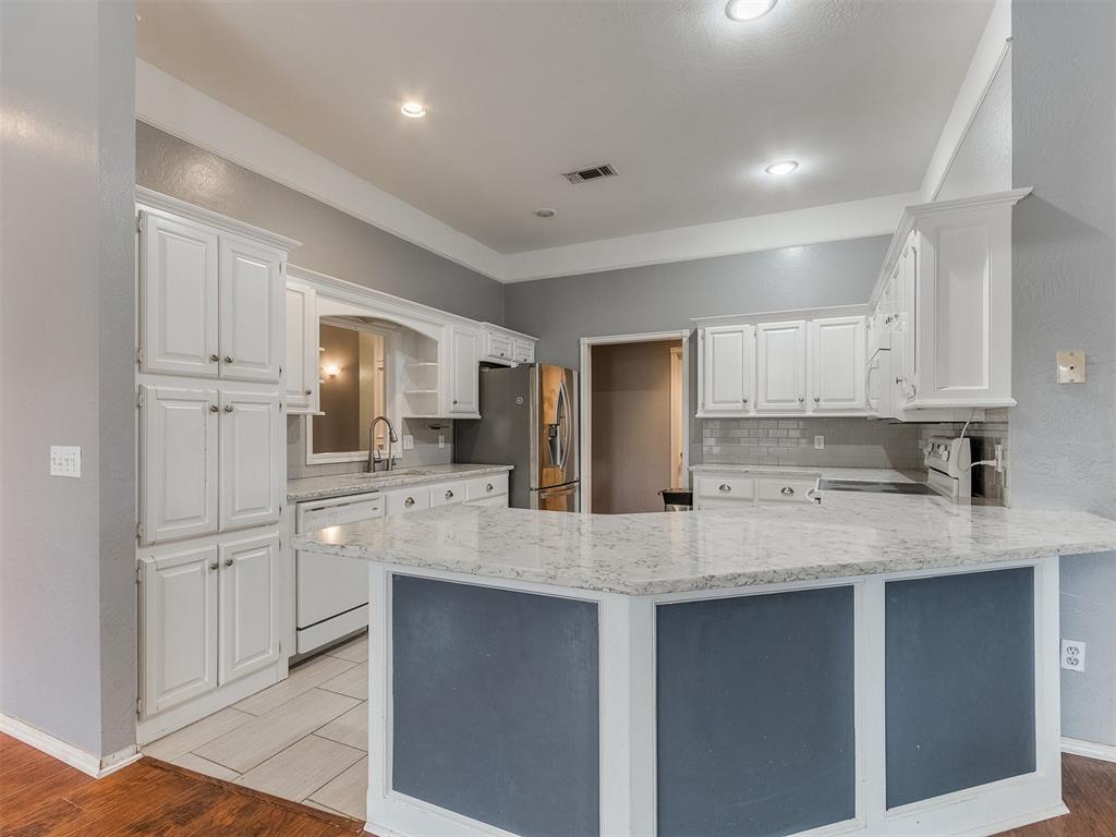 Tessa Hood Realtor – Kitchen with granite island, white cabinets, and tile backsplash at 5879 Mockingbird Ln, Blanchard Oklahoma