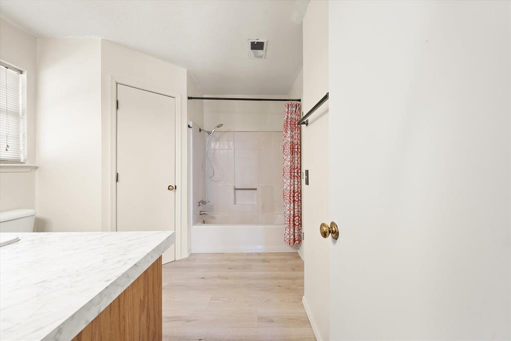 Tessa Hood Realtor – Primary bathroom with tub-shower combo and marble countertop at 2028 Rose Court, Norman Oklahoma
