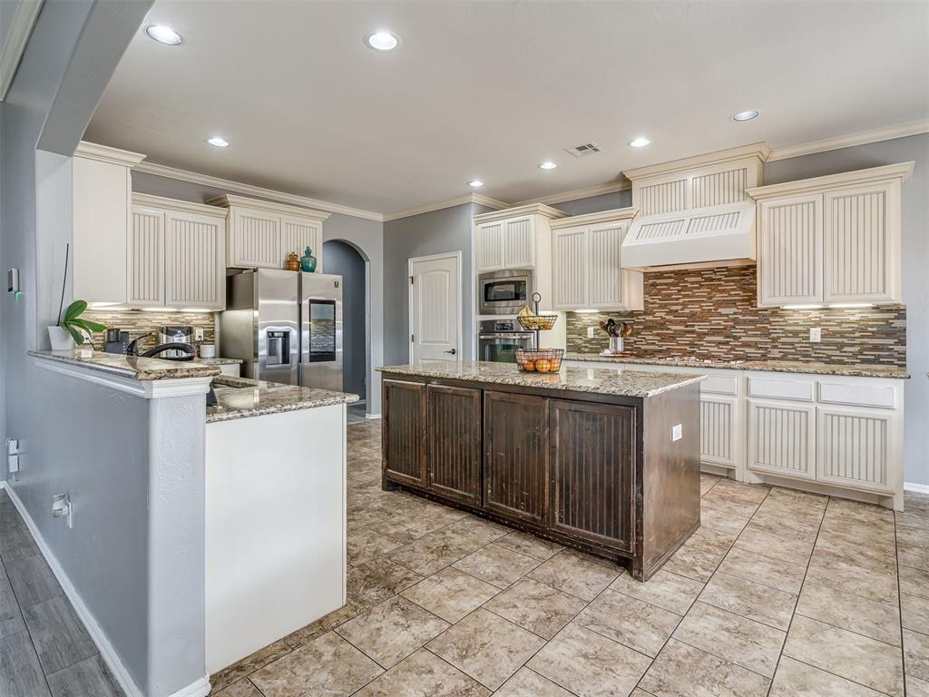 Tessa Hood Realtor – Kitchen with large island, granite counters, and tile backsplash at 5708 SE 148th St, Oklahoma City OK
