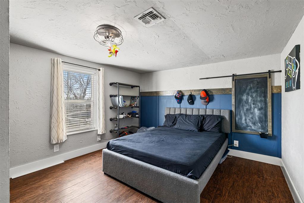 Tessa Hood Realtor – Secondary bedroom with blue accent wall and dark wood floors at 21063 State Hwy 76, Blanchard Oklahoma