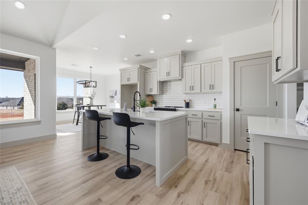 Tessa Hood Realtor – Kitchen island with bar seating and gray shaker cabinets at 2439 Wind River Cir, Blanchard Oklahoma